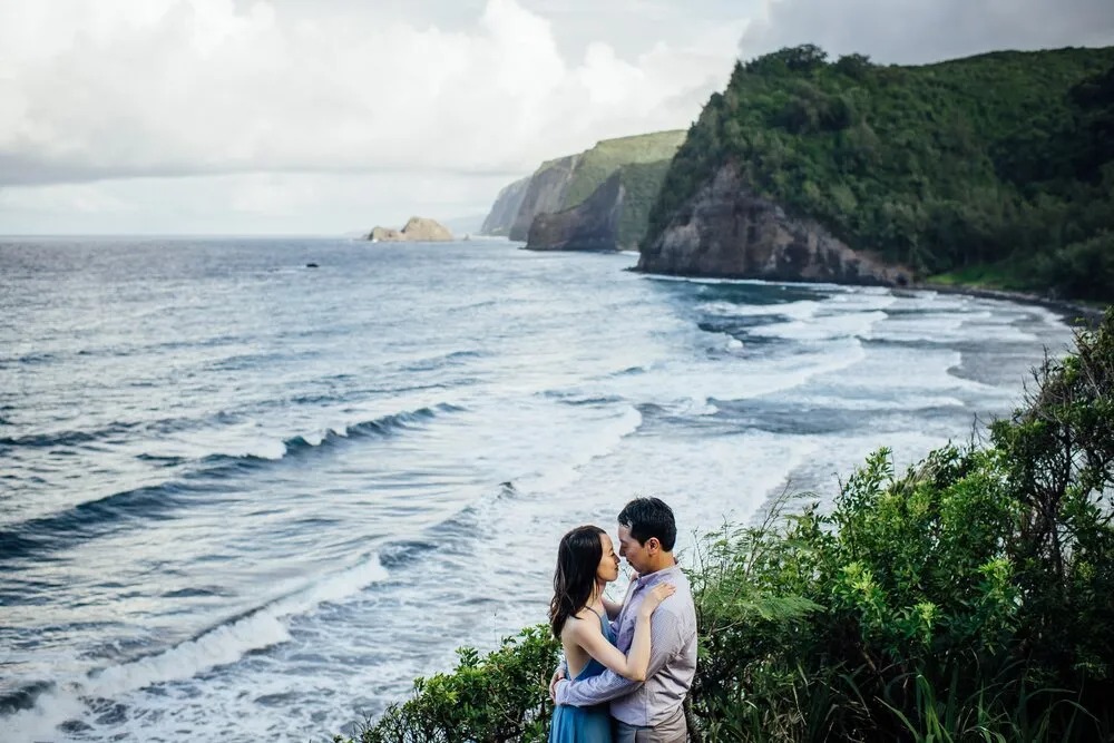 a man and a woman standing in front of a body of water