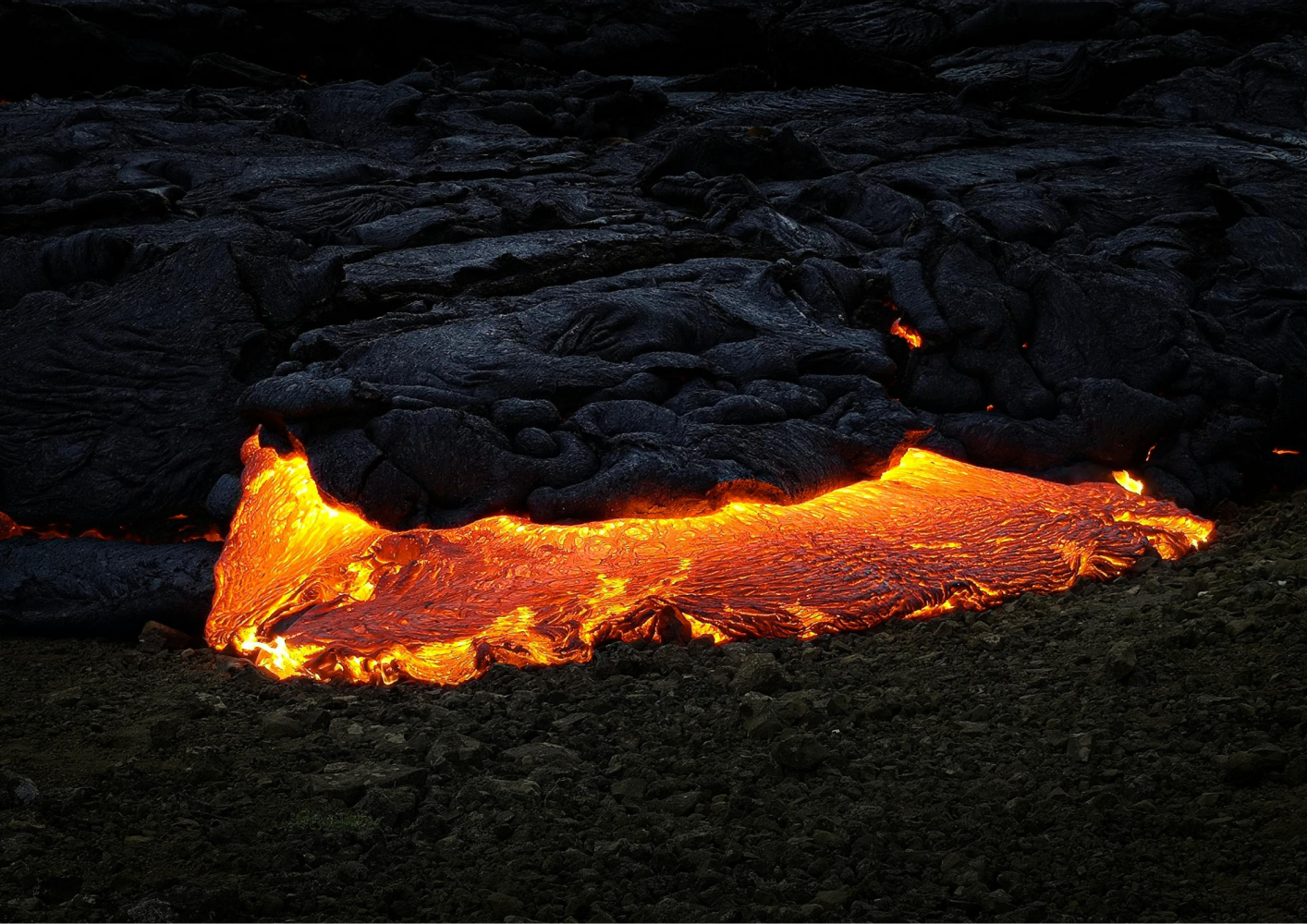 Glowing molten lava flowing beneath dark, solidified crust.