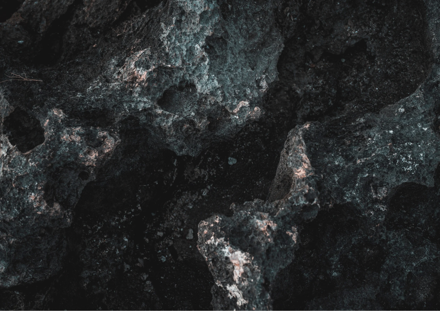 Close-up of dark, textured rock surface with rough, uneven contours.