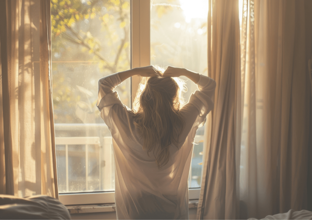 Person stretching by a sunny window with curtains, morning light.