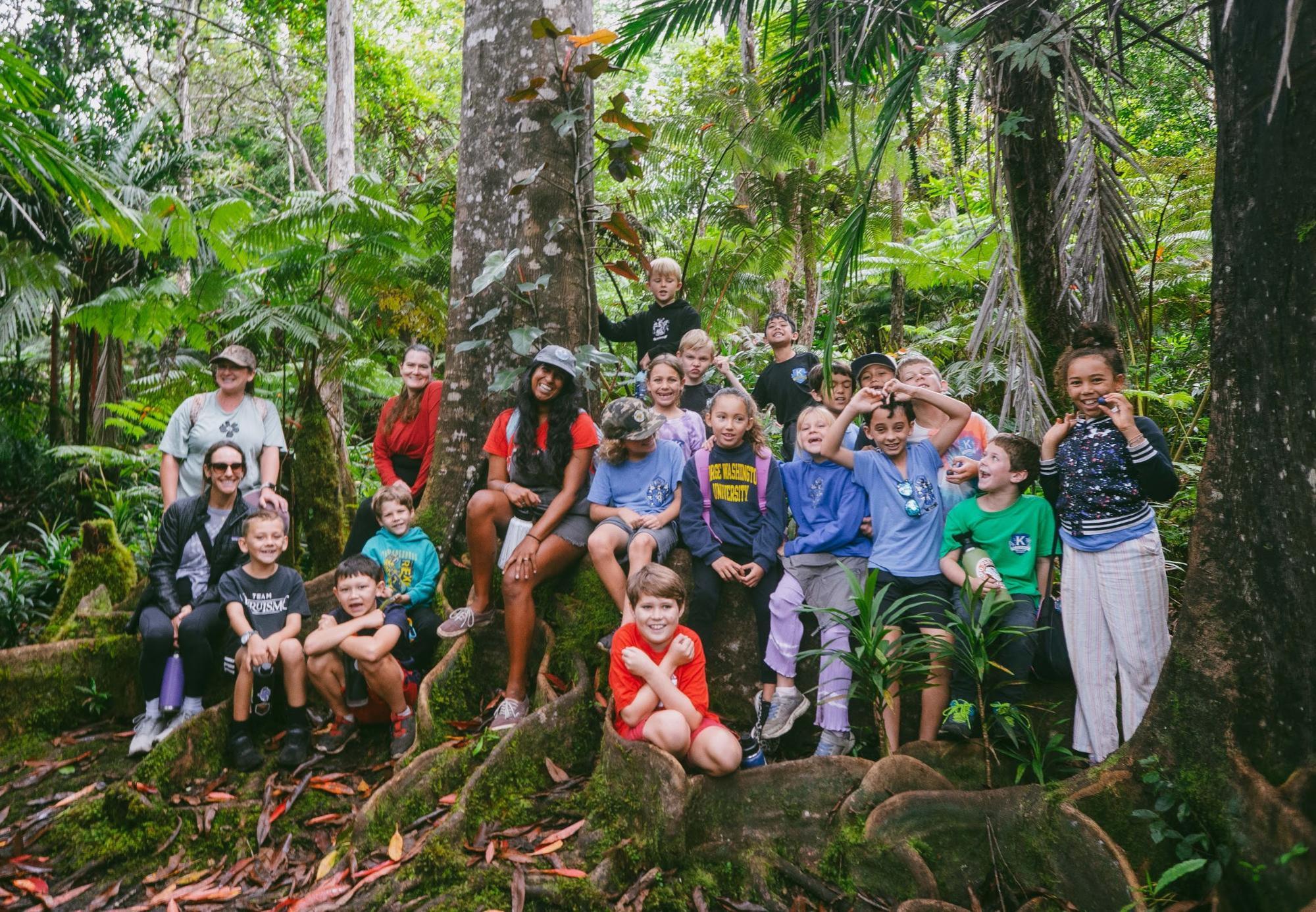 image2 A group of children and adults posing together in a lush forest setting.