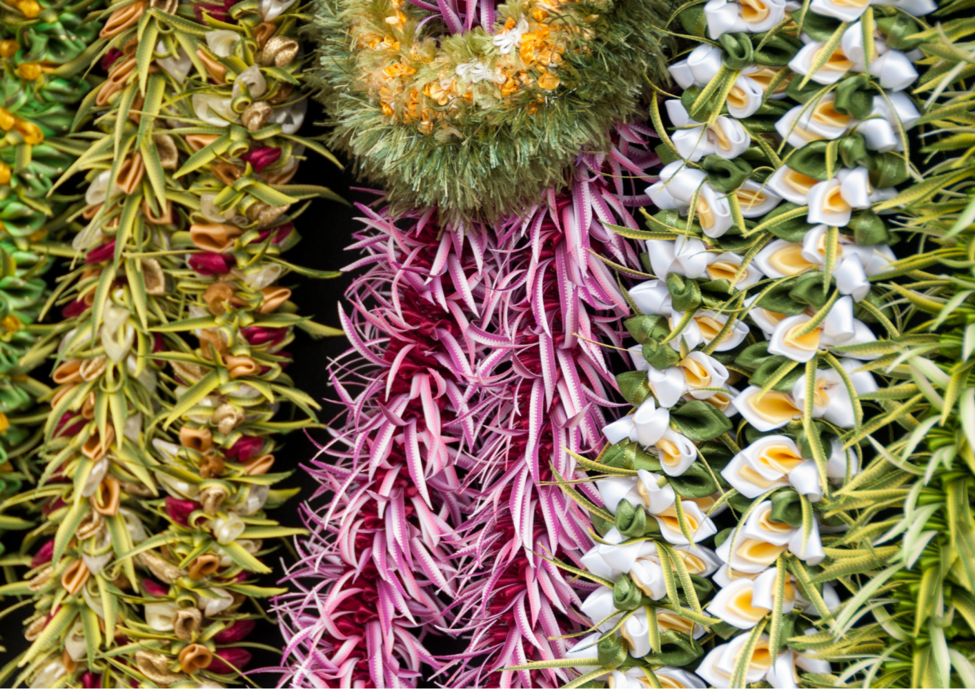 Close-up view of colorful, intricately woven flower leis.
