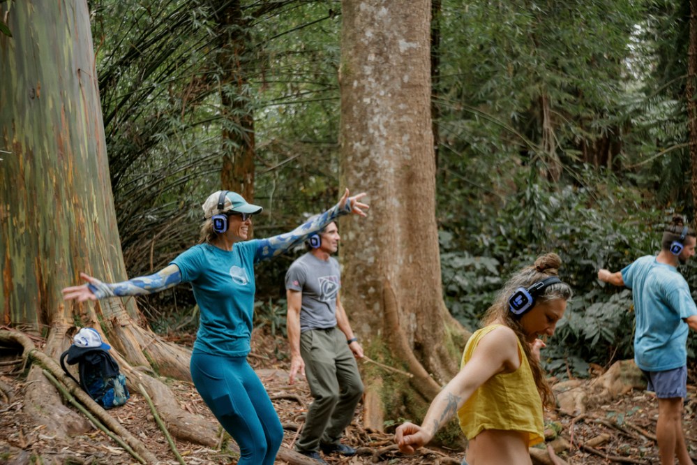 Group of people with headphones dancing in a forest